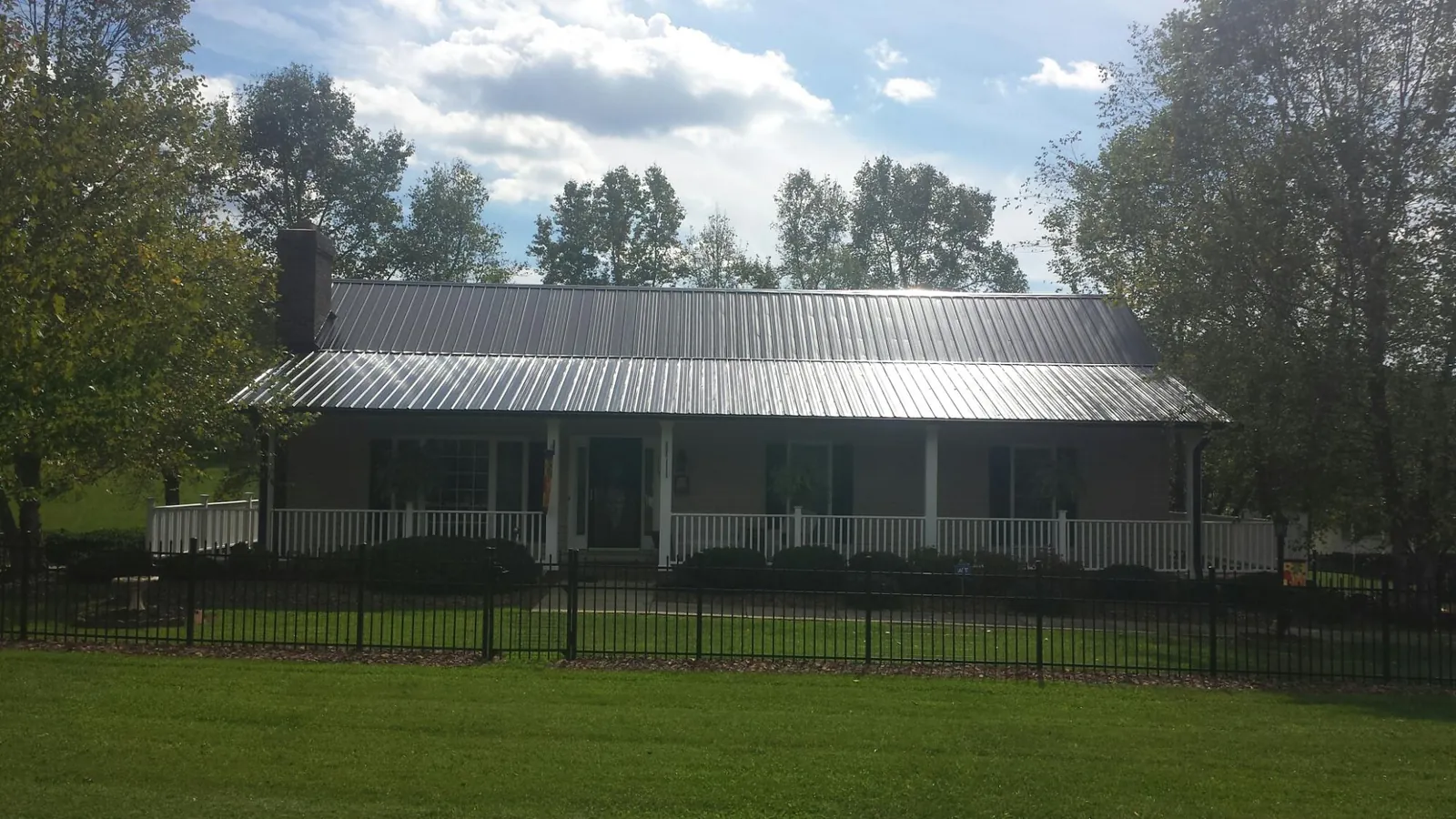 Gray metal roof on a brick ranch with a full width front porch — Gutter Guard Installation work by our crew in Fontana