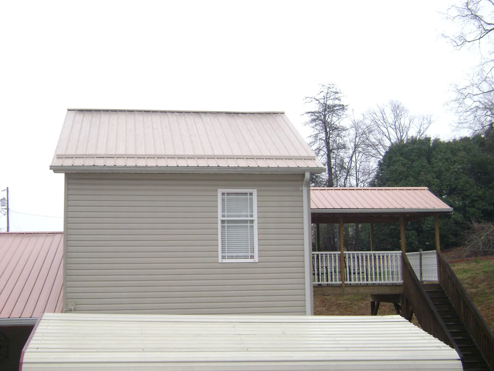 Tan metal roofs on a two story addition and attached porch, from a Roof Replacement job in Fontana